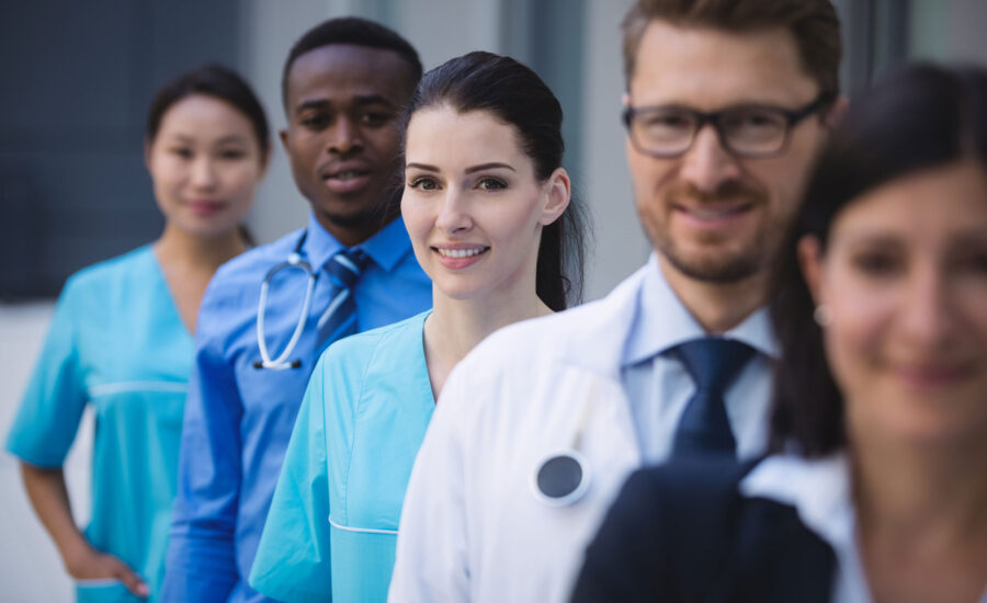 Portrait of smiling doctors standing in row at hospital premises health professionals